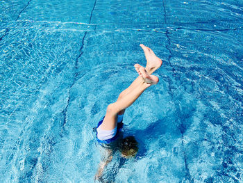 High angle view of boy hand stand in pool