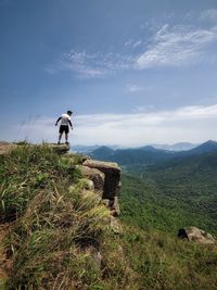 Rear view of man standing on mountain against sky