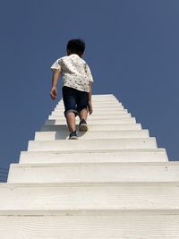 Boy with white stairs up to the sky