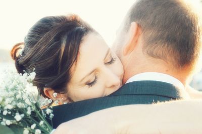 Close-up of bride and groom embracing during wedding on sunny day