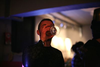 Young man drinking wine during party