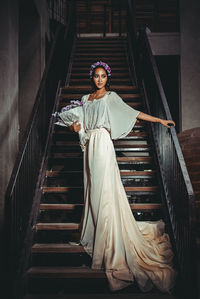 Portrait of young woman standing on stairs