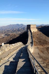 Walkway leading towards mountain against sky