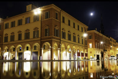 Illuminated building by street at night