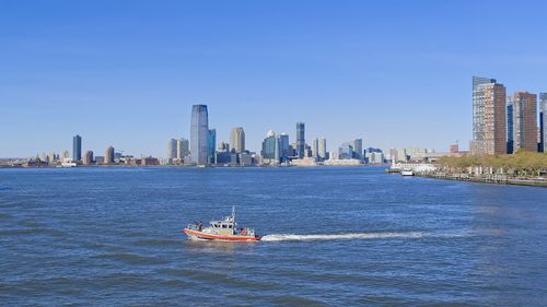 Nautical vessel on sea by buildings in city against sky