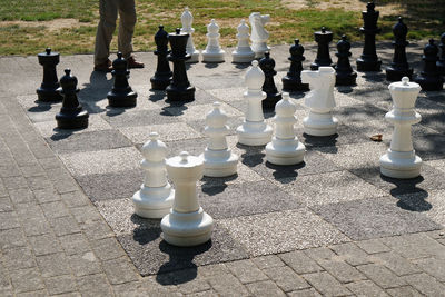 Low section of man standing chess pieces in park during sunny day