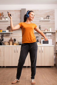 Full length of woman dancing while standing at kitchen