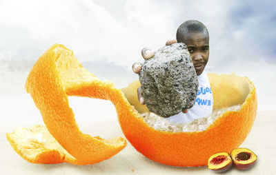 Portrait of man with orange fruit against white background