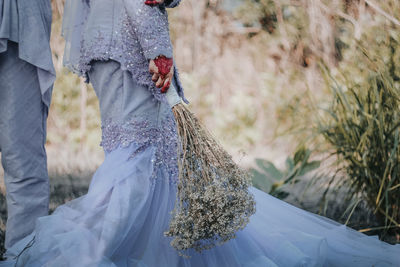 Low section of couple with flowers standing outdoors