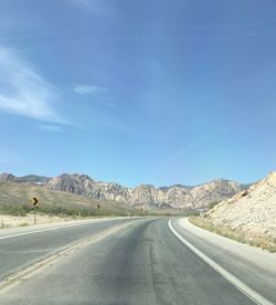 Road leading towards mountains against sky