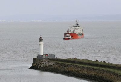 Lighthouse by sea against sky