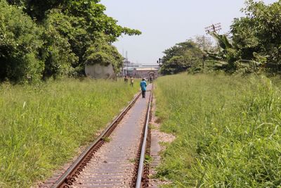 Full length rear view of man walking on railroad track