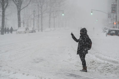 Person taking self portrait while standing on street during snowfall