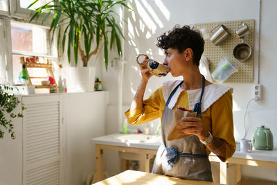 Female ceramist drink coffee and eat snack in art studio at break from master class produce pottery