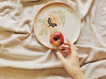 Cropped hand of woman holding apple in plate