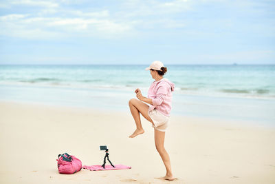 Woman with umbrella on beach against sky