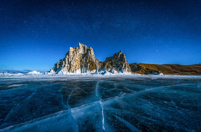 Frozen sea against mountains during winter