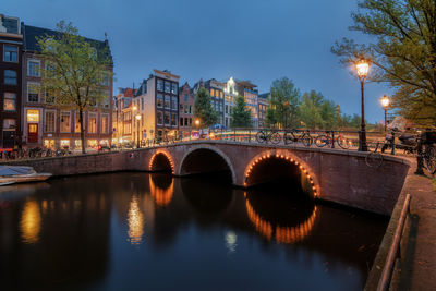 Illuminated bridge over the keizersgracht canal in amsterdam at dusk