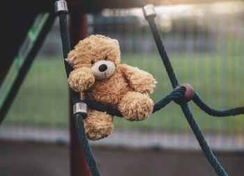 Close-up of stuffed toy hanging on metal fence