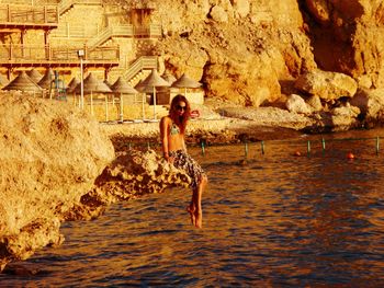 Woman standing on rock by sea