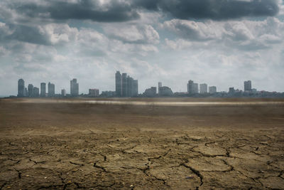 Cracked land against cityscape