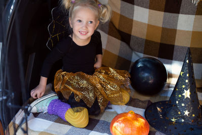 Portrait of cute girl sitting by halloween equipment