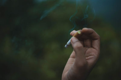 Close-up of hand holding cigarette