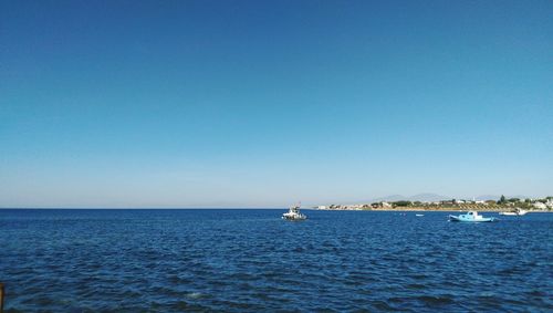 Sailboat sailing in sea against clear blue sky