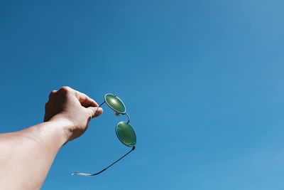 Low angle view of person hand against blue sky