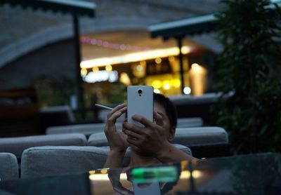 Man holding smart phone and cigarette in outdoor cafe