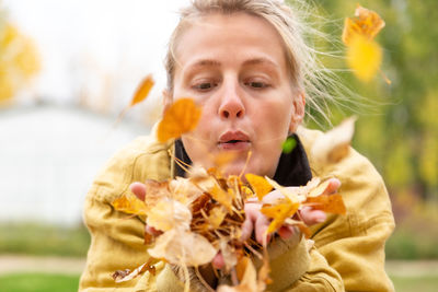 Close-up of woman blowing leaves while standing outdoors