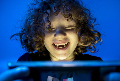 Close-up of smiling girl with curly hair playing video game