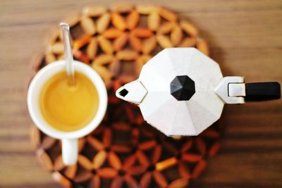 Directly above shot of cup and coffee maker on table