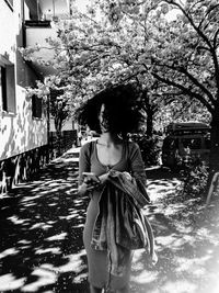 Woman standing by plants against trees