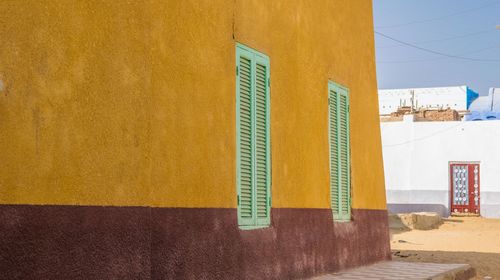 Yellow wall by building against sky