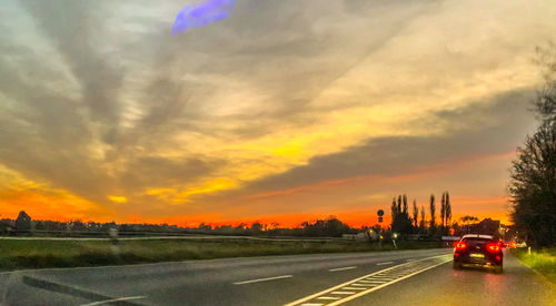 Cars on road against sky during sunset