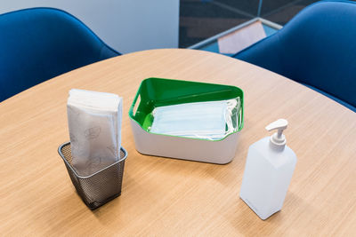 High angle view of hand sanitizer and surgical mask on table