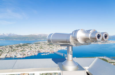 Coin-operated binoculars against sea during sunny day