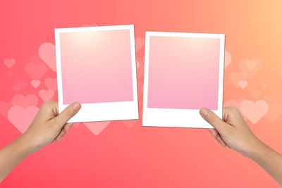 Close-up of hand holding instant print transfer against colored background