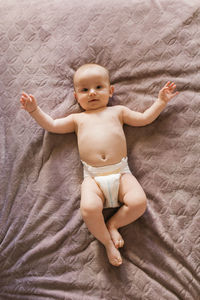 Cute baby in a diaper lying on the bed on his back