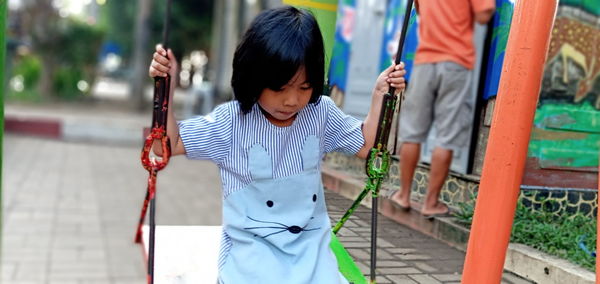 Girl sitting on swing at park