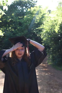 Portrait of a young woman standing against trees