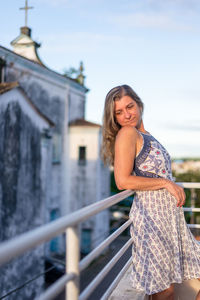 Portrait of smiling young woman standing against building