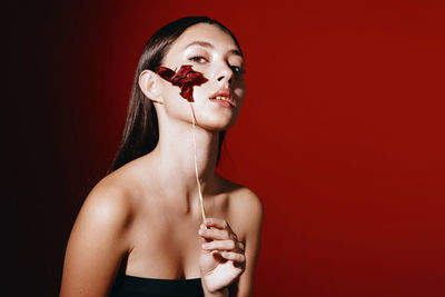 Portrait of young woman against red background