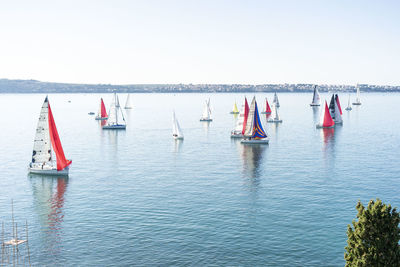 Sailboats in sea against clear sky