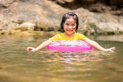 Smiling girl with inflatable ring swimming in lake