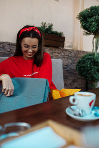 Young woman holding coffee cup on table