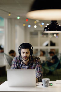 Businessman listening music while working late on laptop in creative office