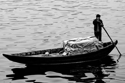 Man standing on fishing boat in lake