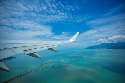 Airplane flying over sea against blue sky